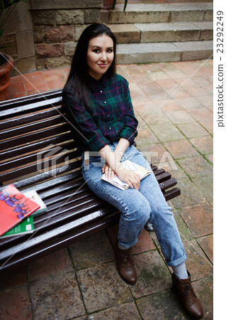 College student relaxing on a bench outdoors College student relaxing on a bench outdoors 23292249
