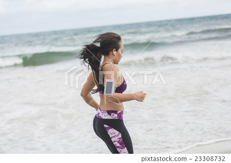 Young female runner jogging on the beach Young female runner jogging on the beach 23308732