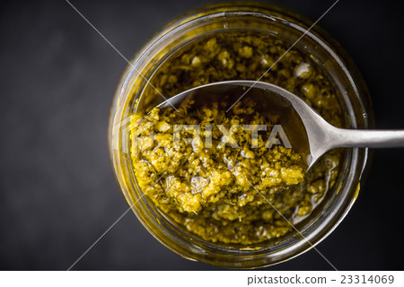 Pesto sauce in the glass jar with spoon top view Pesto sauce in the glass jar with spoon top view 23314069