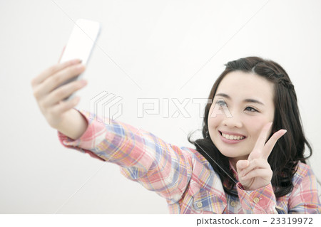 Woman taking pictures with a smartphone Woman taking pictures with a smartphone 23319972