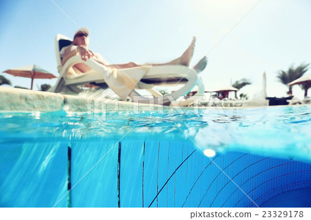 man sunbathing on a sun lounger by the pool 23329178