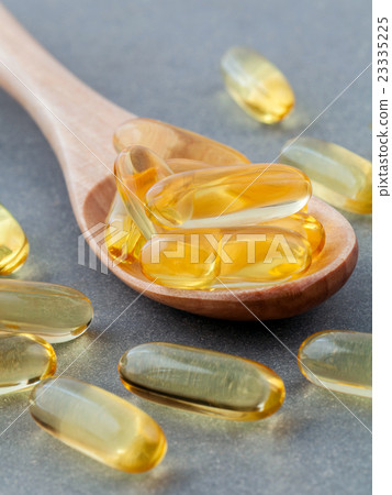 Close up capsules fish oil in wooden spoon . Close up capsules fish oil in wooden spoon . 23335225