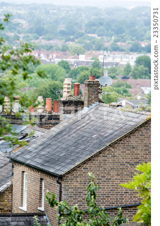 A roof and a chimney of a house standing on a suburban hill in London A roof and a chimney of a house standing on a suburban hill in London 23350731