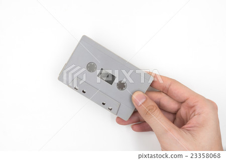 Hand holding cassette tape on white background. 23358068