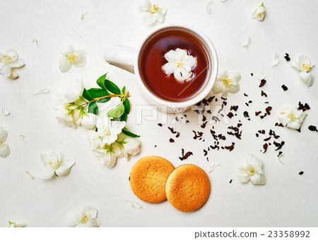 Tea cup, dried and fresh Jasmine flower, biscuits 23358992