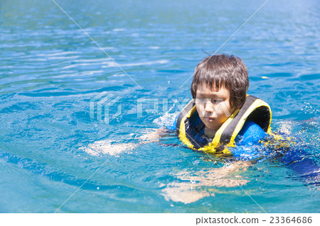 A boy swimming under a life jacket 23364686