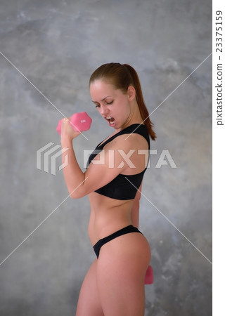 Emotional sports girl shouts, doing exercise with dumbbells Emotional sports girl shouts, doing exercise with dumbbells 23375159