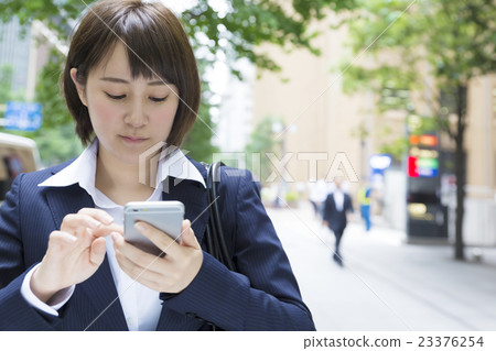 Business woman smaho operation smile outside green marunouchi avenue 23376254