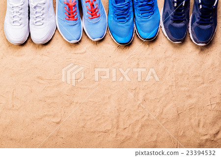 Various sports shoes in a row against sand, studio Various sports shoes in a row against sand, studio 23394532