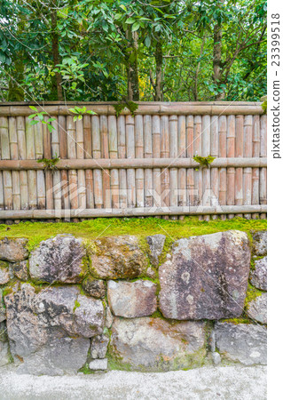 Bamboo fence on stone with green leaves . 23399518