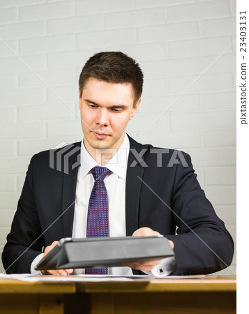 Businessman using his tablet in the office Businessman using his tablet in the office 23403131