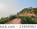 Woman standing shooting mountain road by the sea 23404962
