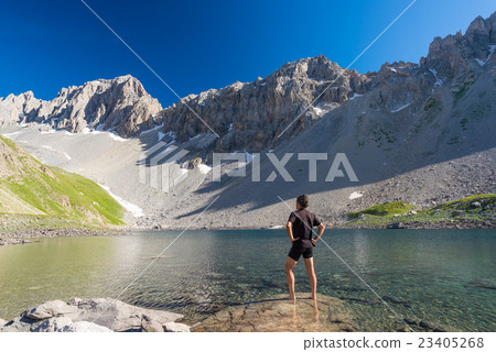 Hiker relaxing at high altitude blue lake Hiker relaxing at high altitude blue lake 23405268