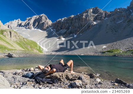 Hiker relaxing at high altitude blue lake Hiker relaxing at high altitude blue lake 23405269