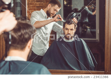 Young handsome barber making haircut of attractive 23411366