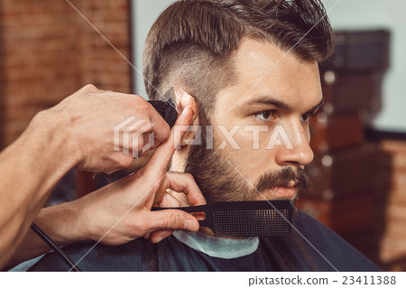 The hands of young barber making haircut to 23411388