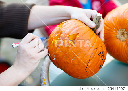 Hollowing out a scary pumpkin to prepare halloween 23413607
