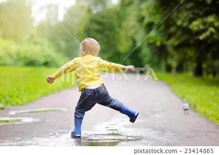 Little boy wearing rain boots jumping in pool of water Little boy wearing rain boots jumping in pool of water 23414865