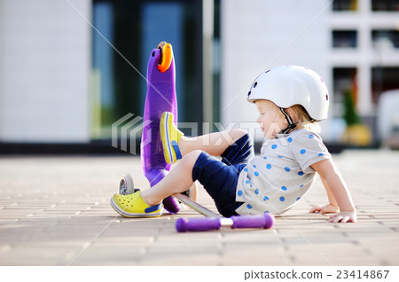 Toddler boy learning to ride scooter 23414867