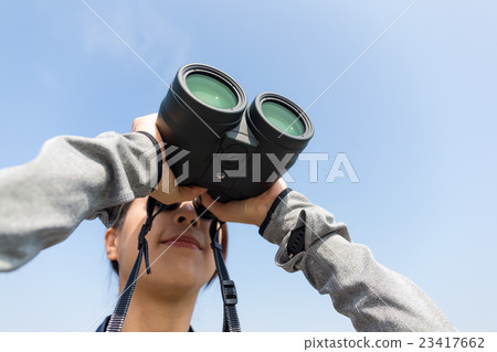 Woman watching though binoculars with clear blue sky 23417662