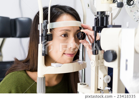 Woman checking vision with tonometer at eye clinic 23418335