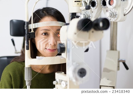 Woman checking vision with equipment Woman checking vision with equipment 23418340