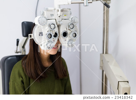 Woman checking on her eye with optometry machine 23418342