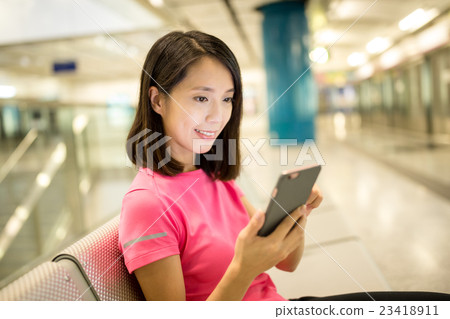 Woman use of smart phone at train platform Woman use of smart phone at train platform 23418911