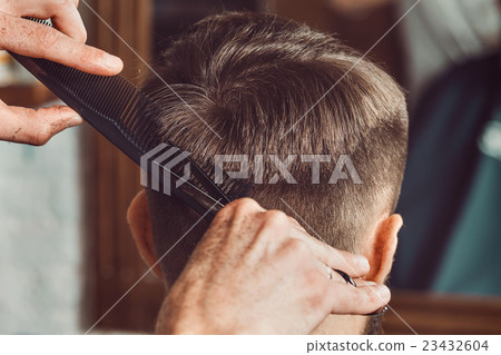 The hands of young barber making haircut to 23432604