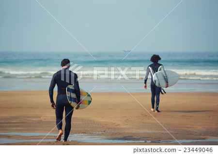 Two professional surfers carrying their surfboards Two professional surfers carrying their surfboards 23449046
