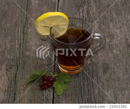 cup of tea with a lemon decorated with currant cup of tea with a lemon decorated with currant 23452381