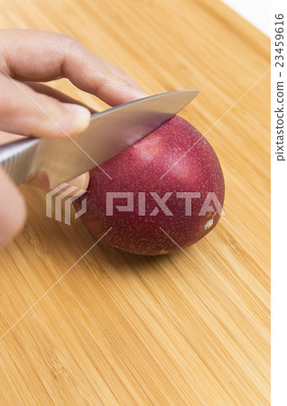 A woman cutting a passion fruit 23459616