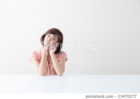 接觸智能手機的中間女性在桌上·白色後面 23470277
