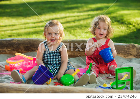 The two little baby girls playing toys in sand The two little baby girls playing toys in sand 23474246