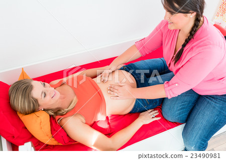 Midwife exanimating belly of pregnant woman Midwife exanimating belly of pregnant woman 23490981