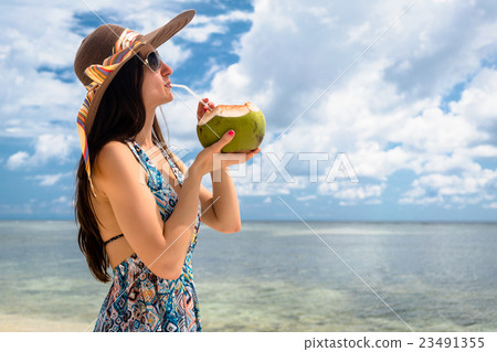 Woman tourist drinking coconut milk at beach 23491355