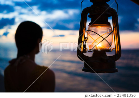 Woman in lantern shine looking to sea at sunset 23491356