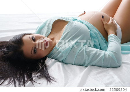 Pregnant woman posing looking at camera 23509204