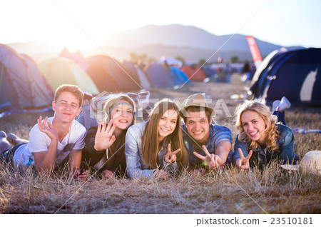 Teenagers lying on the ground in front of tents Teenagers lying on the ground in front of tents 23510181