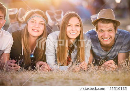 Teenagers lying on the ground in front of tents Teenagers lying on the ground in front of tents 23510185