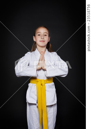 Child girl in karate suit with yellow belt show Child girl in karate suit with yellow belt show 23518756