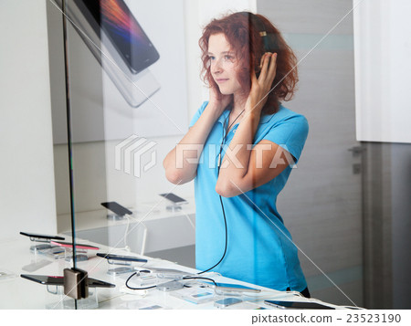 woman chooses smartphone in a store woman chooses smartphone in a store 23523190