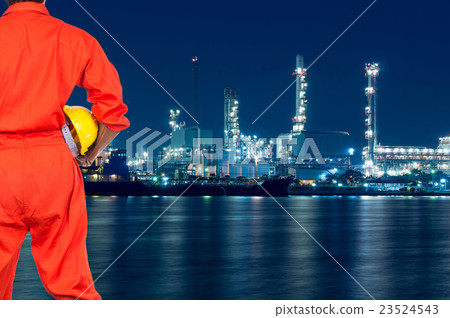 Asian engineers holding a yellow hardhat on Oil and gas refinery or Petrochemical factory at twilight time, industrial concept 23524543