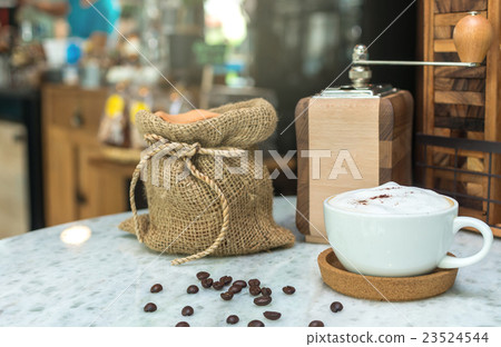 Cappuccino coffee cup on wood table with traditional coffee beans and grinder Cappuccino coffee cup on wood table with traditional coffee beans and grinder 23524544