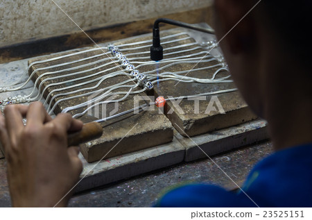 Close up of Jeweler crafting silver necklace with flame torch. 23525151