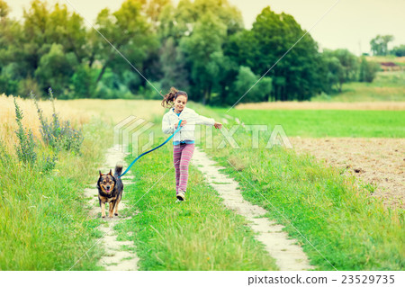 Little girl running with dog in countryside 23529735