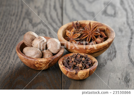 anise stars cloves and nutmeg in olive bowl on oak 23530866
