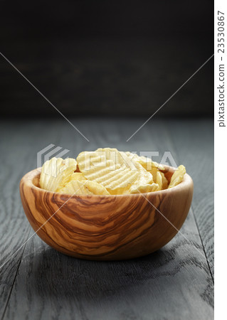 rippled organic chips in wood bowl on wooden table 23530867