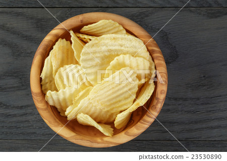 rippled organic chips in wood bowl on wooden table rippled organic chips in wood bowl on wooden table 23530890