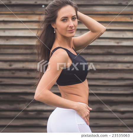 Young fit woman standing near wall outdoors 23535063